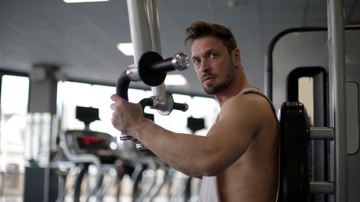 Focused man working out in a gym, showcasing biceps and determination.